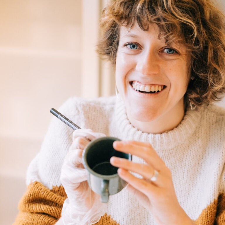 Roos de Studio Roos, entrain de peindre un mug.